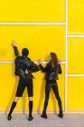 Couple de mode posant sur un mur jaune — Photo de stock