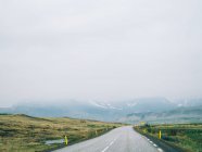 Road leading to foggy montains — Stock Photo