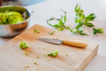 Board with broccoli slices and knife — Stock Photo
