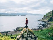 Девушка на камне и смотрит на озеро — стоковое фото