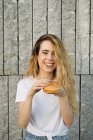 Chica sonriente comiendo hamburguesa - foto de stock