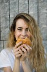 Chica sonriente comiendo hamburguesa - foto de stock