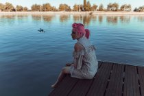 Дівчина сидить на озерному пірсі — стокове фото