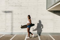 Stylish woman with board walking at street — Stock Photo