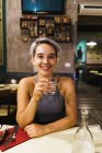 Молода жінка з випивкою в барі — стокове фото