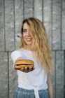 Sonriente chica mostrando hamburguesa - foto de stock