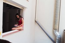 Menina sentada na soleira da janela — Fotografia de Stock