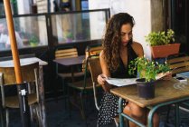 Girl in cafe reading map — Stock Photo