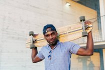 Stylish black man posing with long board — Stock Photo