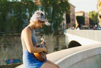 Chica jugando pequeña guitarra en la calle - foto de stock