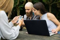 Friends with gadgets in park — Stock Photo