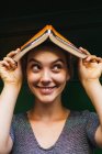 Charmantes Mädchen posiert mit Buch auf dem Kopf — Stockfoto