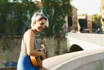 Дівчина грає на маленькій гітарі на вулиці — стокове фото