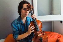 Schöne Frau sitzt mit Geige — Stockfoto