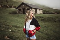 Junge Frau steht über altem Gebäude im Bergtal — Stockfoto