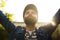 Portrait of man in cap and denim jacket holding hands up and  looking happy. — Stock Photo