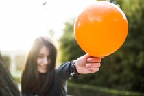 Young brunette holding balloon and in sunlight. — Stock Photo