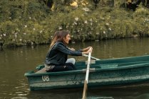 Вид збоку пара веслує разом на човні в парковому озері — стокове фото