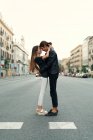 Side view of young couple embracing on road in street scene — Stock Photo