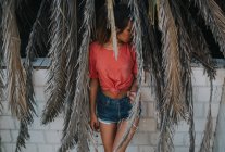 Schüchterne Frau posiert in trockenen Palmblättern — Stockfoto