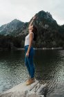 Donna in piedi su pietra al lago — Foto stock