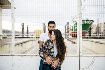 Man embracing girl over industrial wharf backdrop — Stock Photo