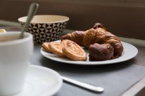 Teller mit Croissant und Keksen auf dem Frühstückstisch — Stockfoto