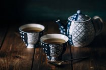 Ainda vida de xícaras de porcelana de chá quente e panela na mesa de madeira
. — Fotografia de Stock