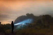 Homme avec lampe de poche la nuit dans les montagnes sous un épais brouillard — Photo de stock
