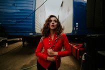 Woman in red coat posing between trailers — Stock Photo