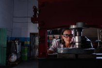 Женщина-механик носит защитные гуглы, работающие гидравлический пресс в гараже — стоковое фото