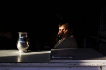 ÍNDIA - 3 de outubro de 2011: Homem de terno sentado atrás da mesa com jarro e olhando para a câmera . — Fotografia de Stock