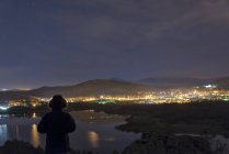 Вид сзади на человека на фоне освещенного городского пейзажа — стоковое фото