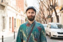 Cheerful bearded man smiling with eyes at camera in city street — Stock Photo
