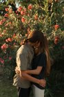 Porträt eines sich umarmenden Paares, das sich über blühenden Pflanzen küsst — Stockfoto