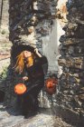 Ragazza in cappello da strega posa a muro di pietra — Foto stock