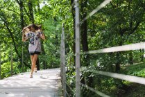 Young woman running on boardwalk in forest — Stock Photo