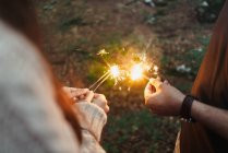 Hands with sparklers in woods — Stock Photo