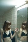 Chica joven en sujetador posando en el espejo en el baño - foto de stock