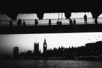 Vista ad angolo basso di sagome su brdige guardando visite turistiche a Londra . — Foto stock
