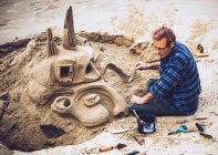 Человек строит замок из песка — стоковое фото
