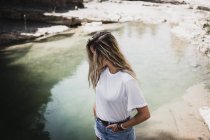 Donna bionda in piedi sulla riva del lago — Foto stock