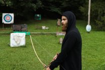Bearded man practicing archery in school — Stock Photo