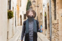 Portrait of bearded man wearing hat spitting and spraying water at street. — Stock Photo
