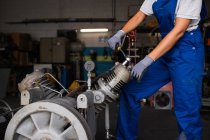 Low section of female mechanic fixing  compressor engine with wrench — Stock Photo