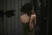 Visão traseira da jovem mulher em vestido cáqui olhando para longe — Fotografia de Stock