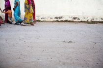 Crop women wearing colorful sari walking on street with child. — Stock Photo