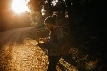 Человек просматривает мобильный телефон на лесной дороге — стоковое фото