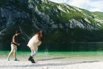 Casal jogando pedras no lago da montanha — Fotografia de Stock