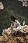 Брюнетка жінка, сидячи на камінь над лісом на тлі — стокове фото